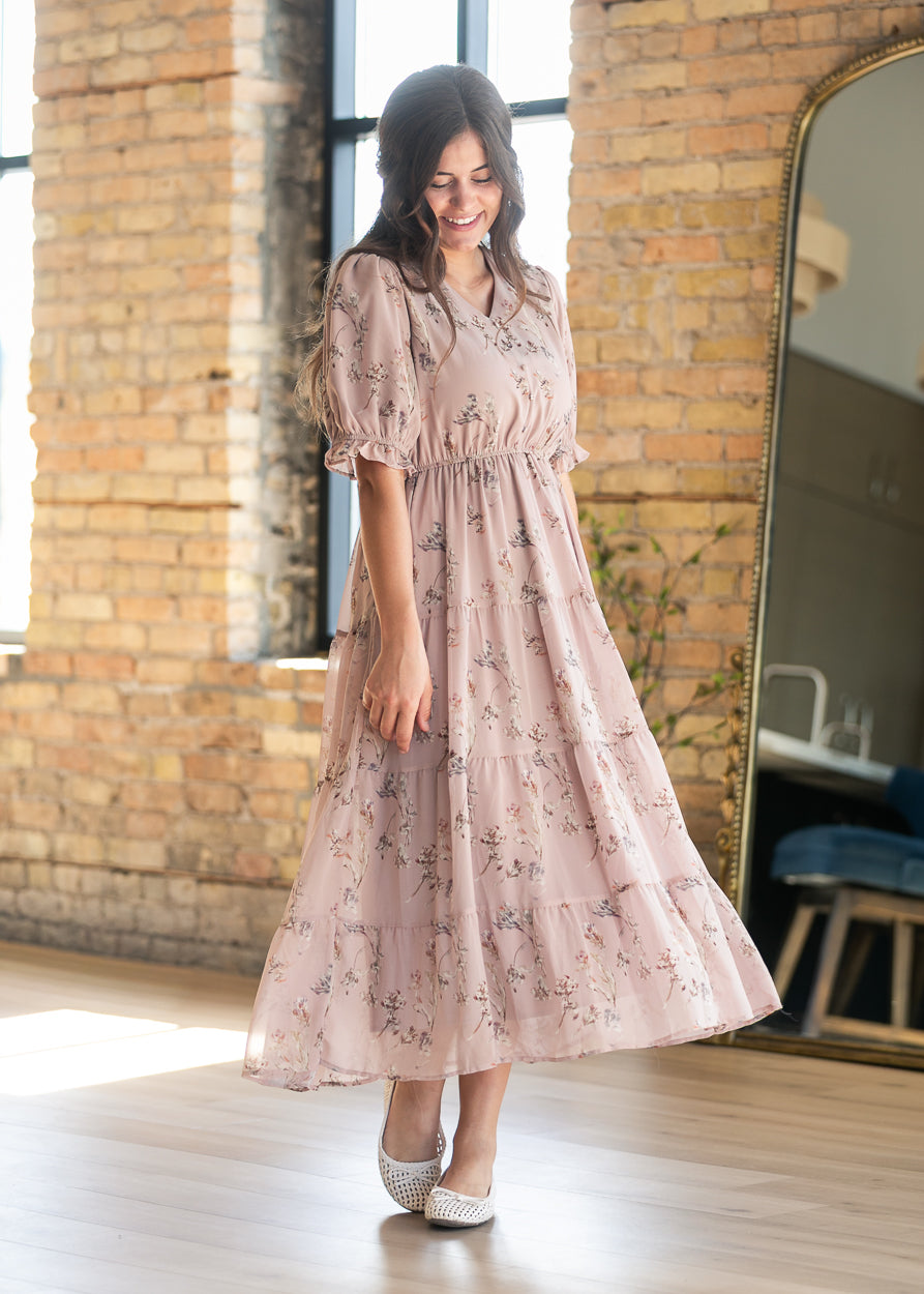 Blush pink floral tiered maxi dress with V-neckline and short puff sleeves, styled with woven flats.
