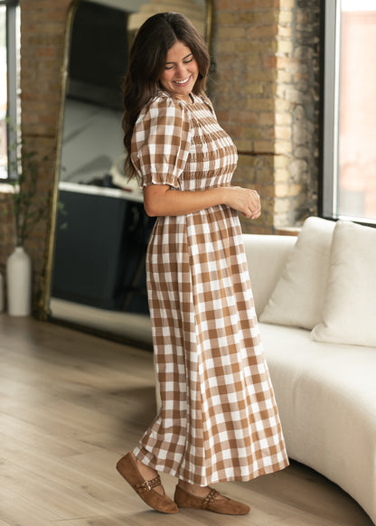 Brown plaid short sleeve midi dress in side view, showing the flowing lined skirt and smocked bodice.
