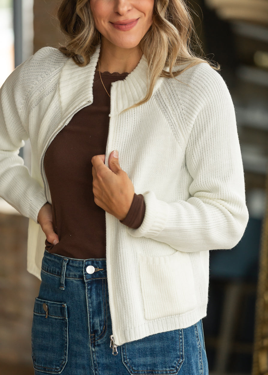Cream two-way zip sweater jacket worn open over a brown layering top