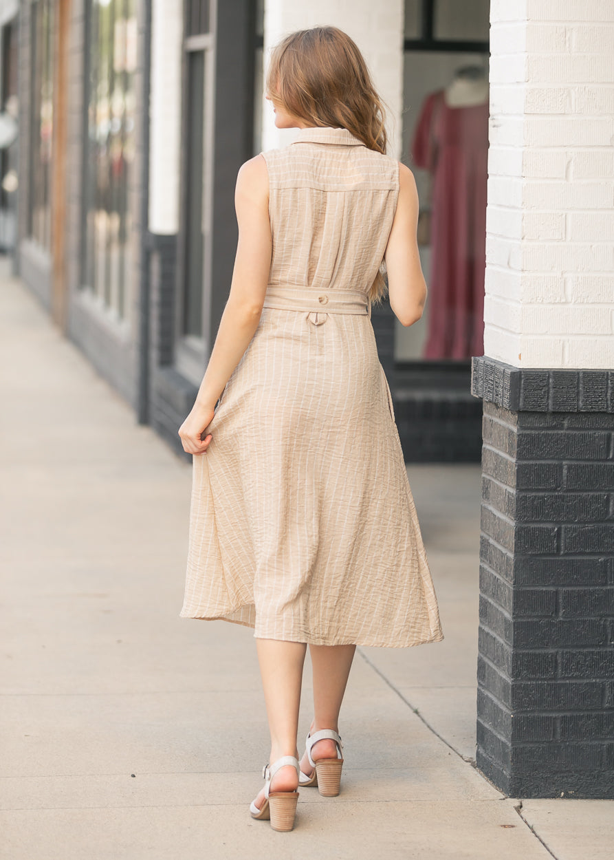 Back view of sand beige striped midi dress with collared neckline and flowing midi-length skirt.