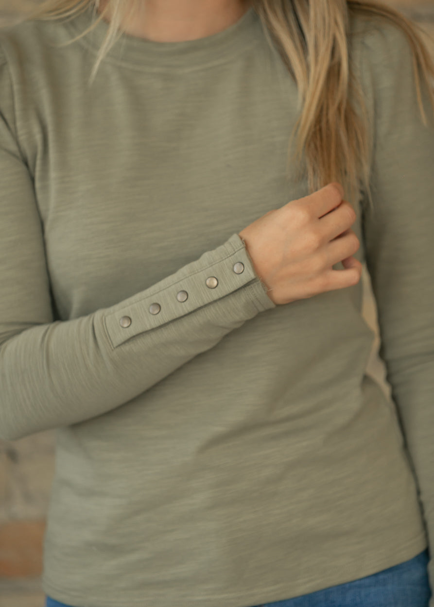 Close-up of sage long sleeve top showing textured slub knit fabric and functional metal cuff snaps.