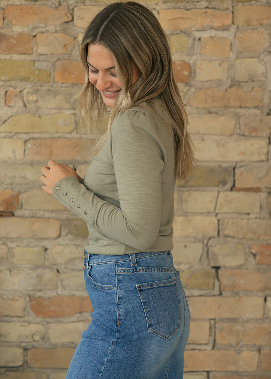Side view of sage slub knit top with long sleeve and functional snap cuff detail.
