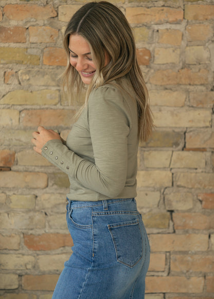 Side view of sage slub knit top with long sleeve and functional snap cuff detail.
