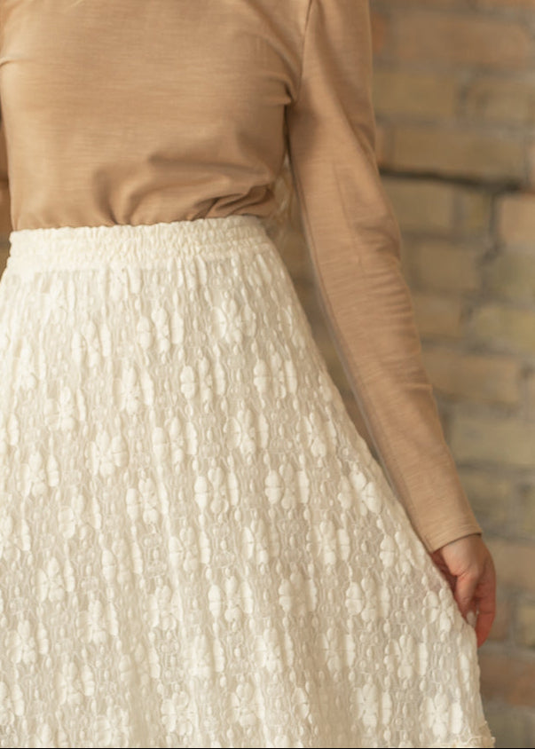 Close-up of ivory floral lace skirt showing the elastic waistband and textured floral lace pattern.