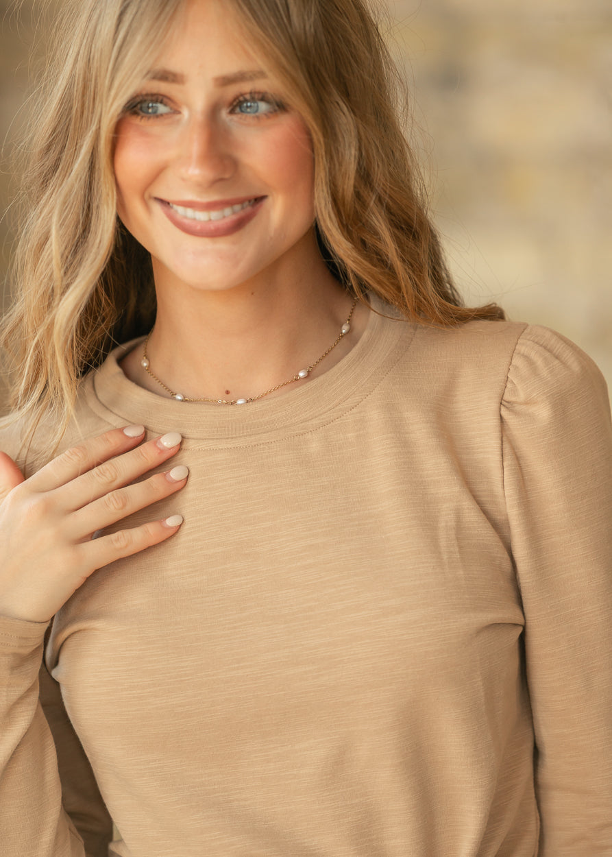 Taupe slub knit long sleeve top with subtle puff shoulders and a fitted silhouette.