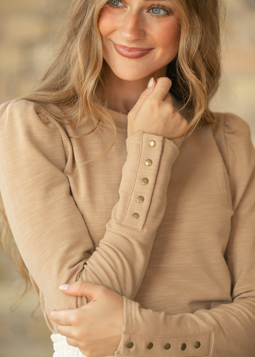 Close-up of taupe long sleeve top showing functional metal snaps along the cuff.