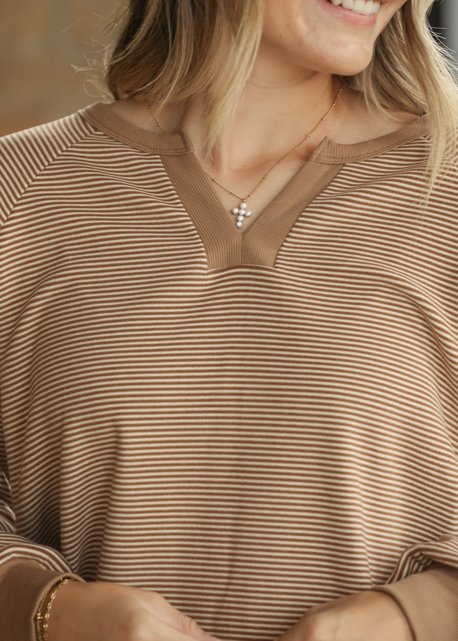 Close-up of brown and ivory stripe top showing the split neckline and contrast ribbed trim.