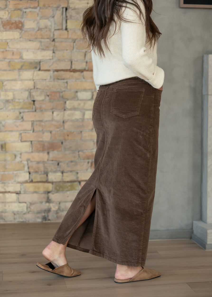 Side view of brown corduroy maxi skirt showing the back slit and ankle-length cut.