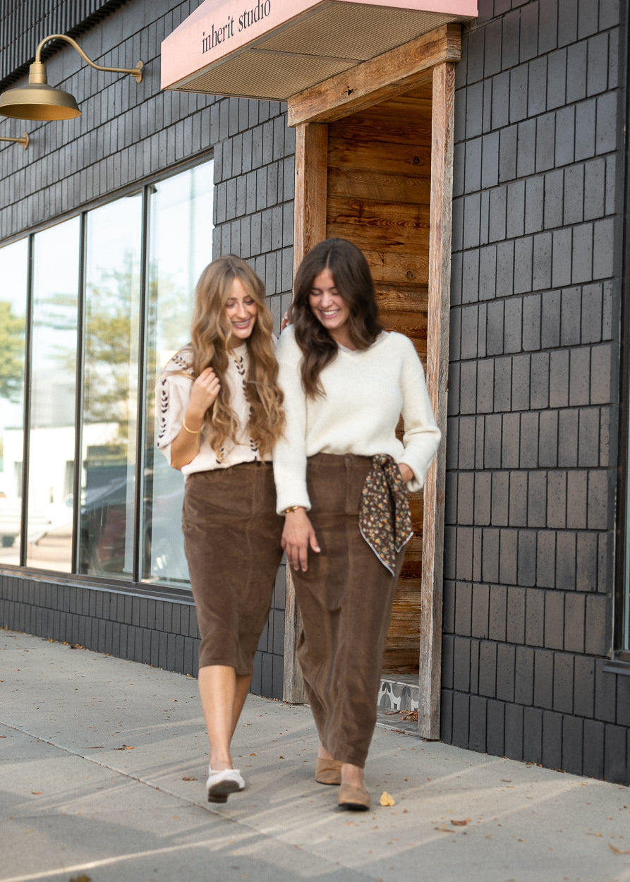 Brown corduroy maxi skirt styled outdoors with a cream sweater for an easy fall outfit.