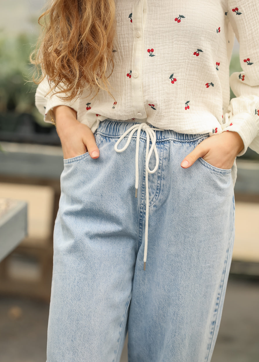 Close-up of elastic drawstring waistband on light wash jeans