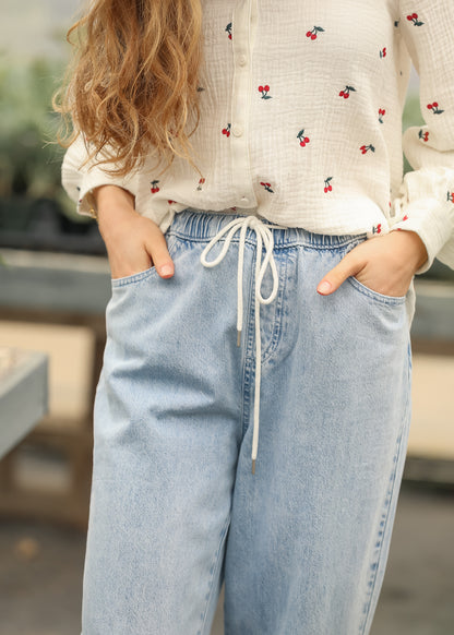 Close-up of elastic drawstring waistband on light wash jeans
