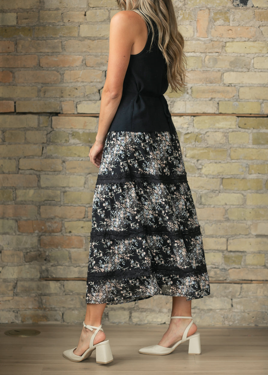 Back of black floral midi skirt showing the flowy tiered silhouette and ankle-skimming length.