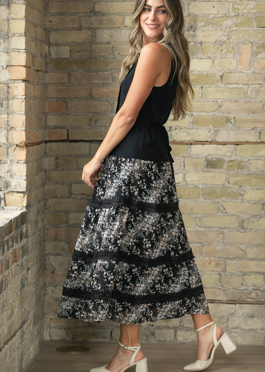 Black floral tiered midi skirt with lace trim styled with a sleeveless black top and cream heels.