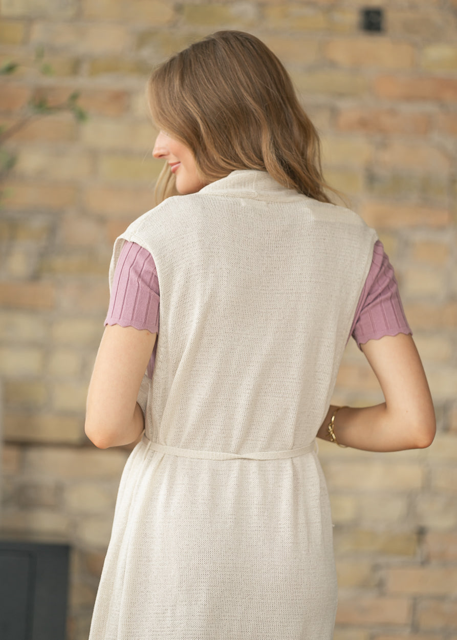 Sleeveless belted cardigan styled over a ribbed midi dress