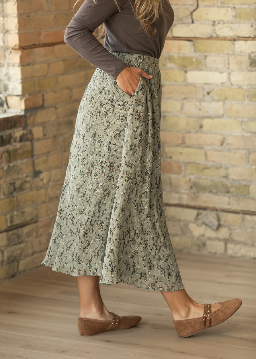 Close-up of sage floral midi skirt showing textured fabric, elastic waistband, and functional side pocket.