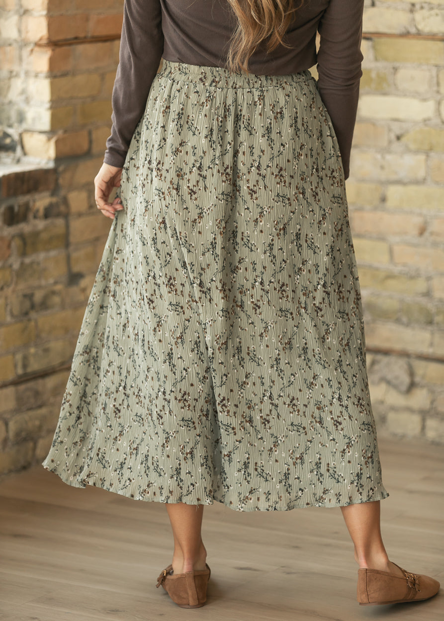 Back of sage floral midi skirt showing elastic waistband, textured floral fabric, and flowy drape.