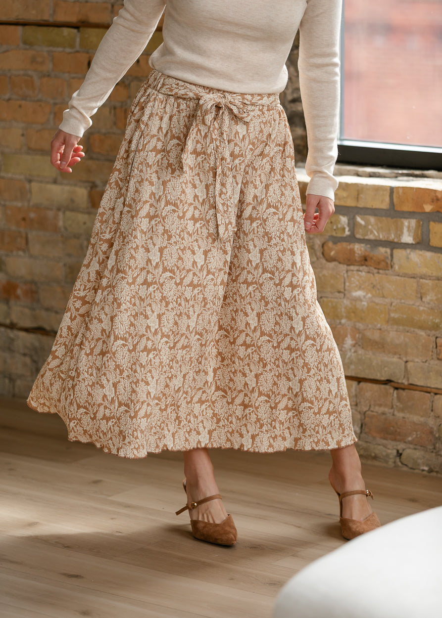 Flowing taupe floral midi skirt with textured fabric, tie waist, and cream floral print.