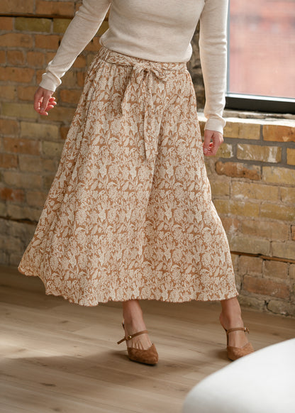 Flowing taupe floral midi skirt with textured fabric, tie waist, and cream floral print.