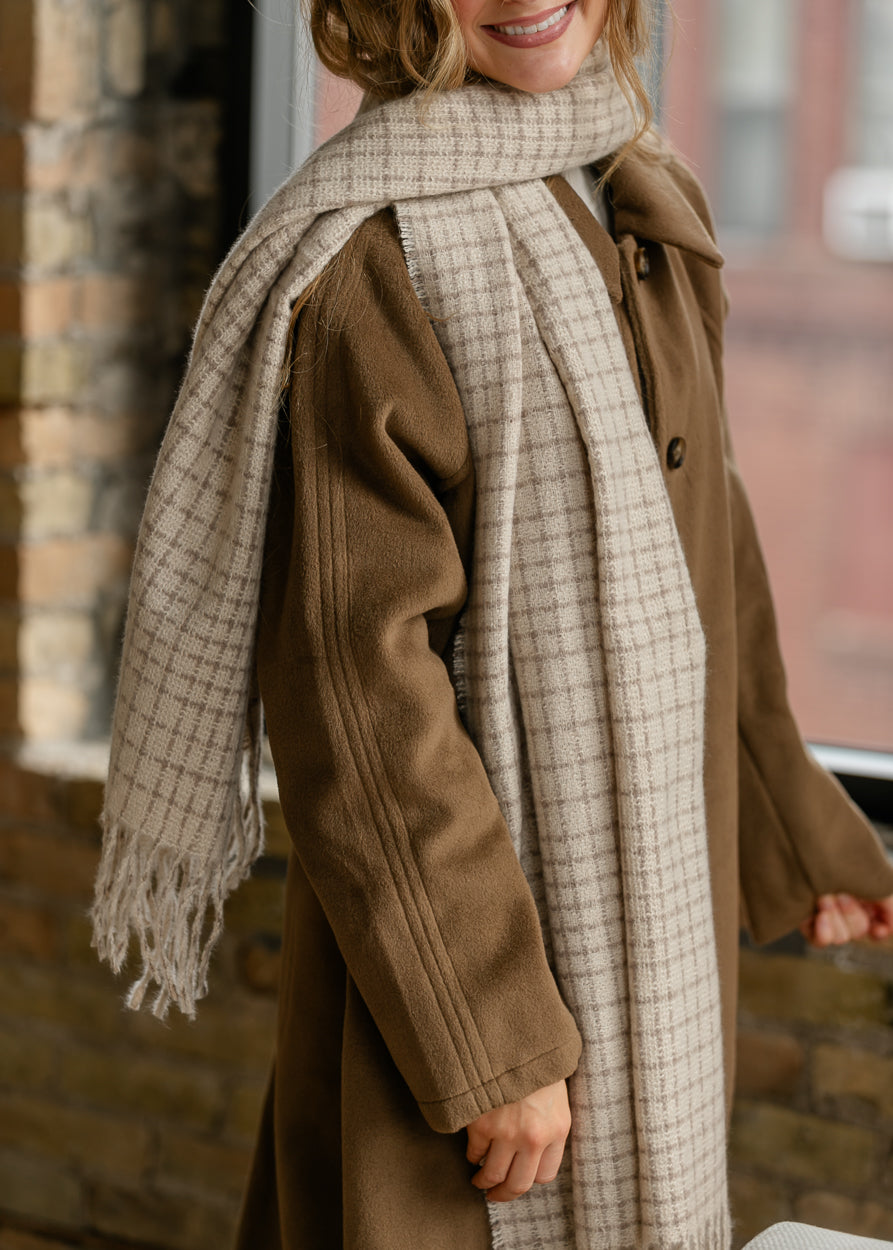 Ivory and taupe woven scarf styled over a brown coat with a relaxed draped finish.
