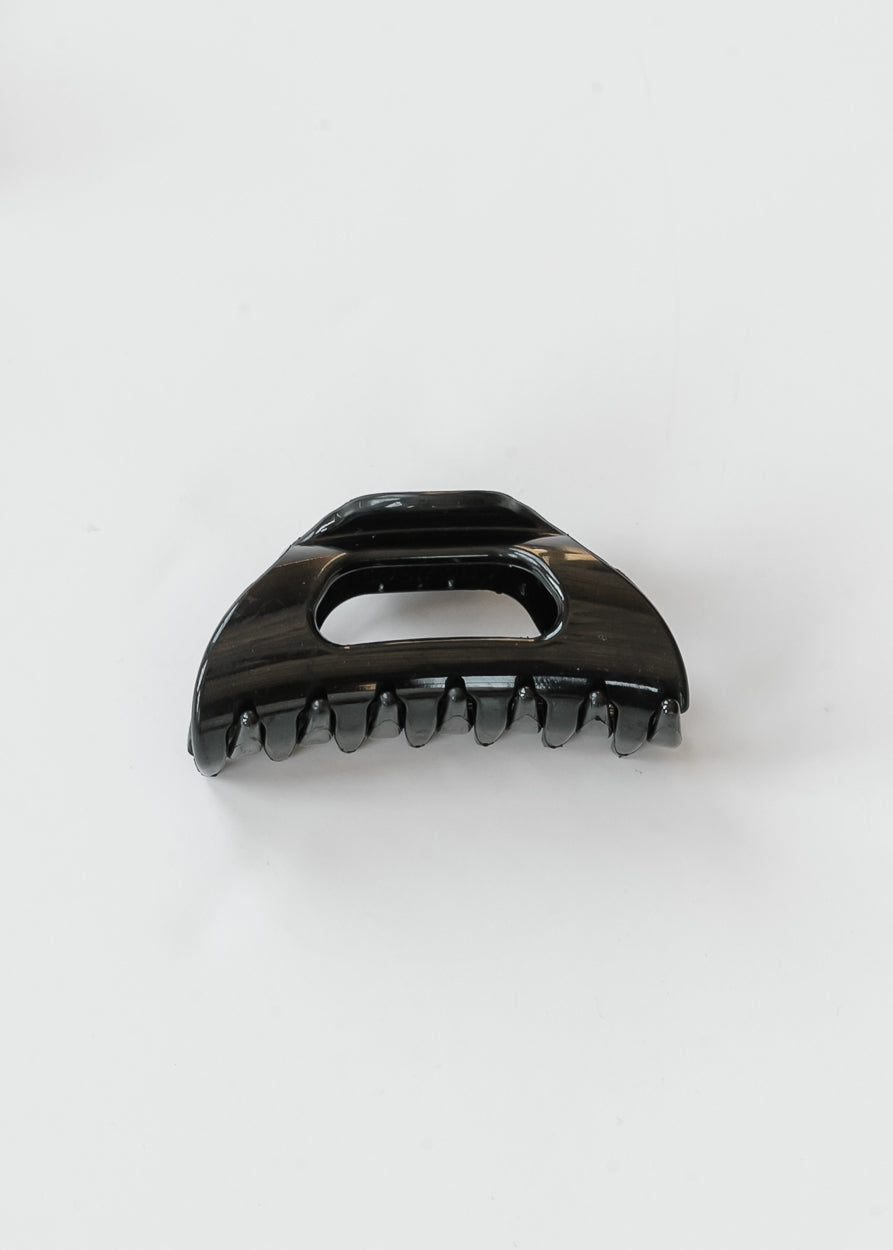 Glossy black flexible claw clip shown from the front with curved claws and open center.