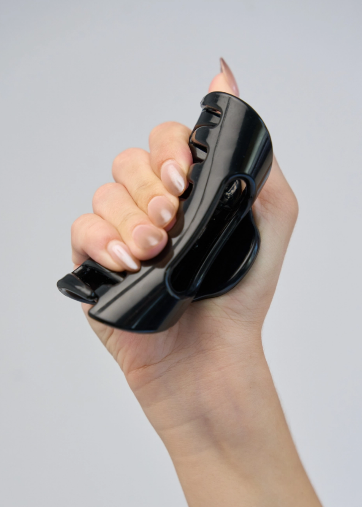 Black flexible claw clip bent in hand to show its soft, bendable construction.