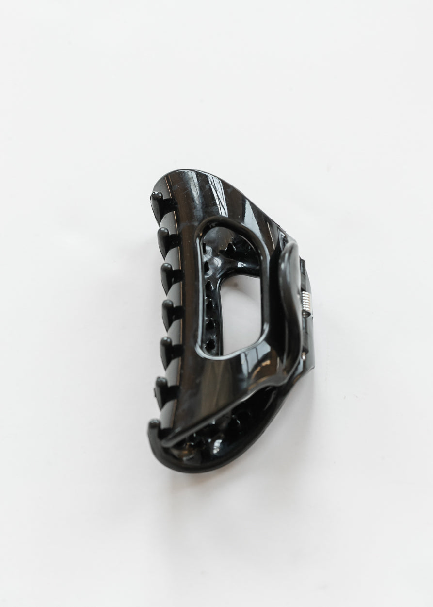 Black flexible claw clip with curved teeth and open center detail on a white background.