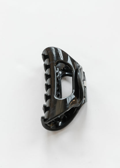 Black flexible claw clip with curved teeth and open center detail on a white background.