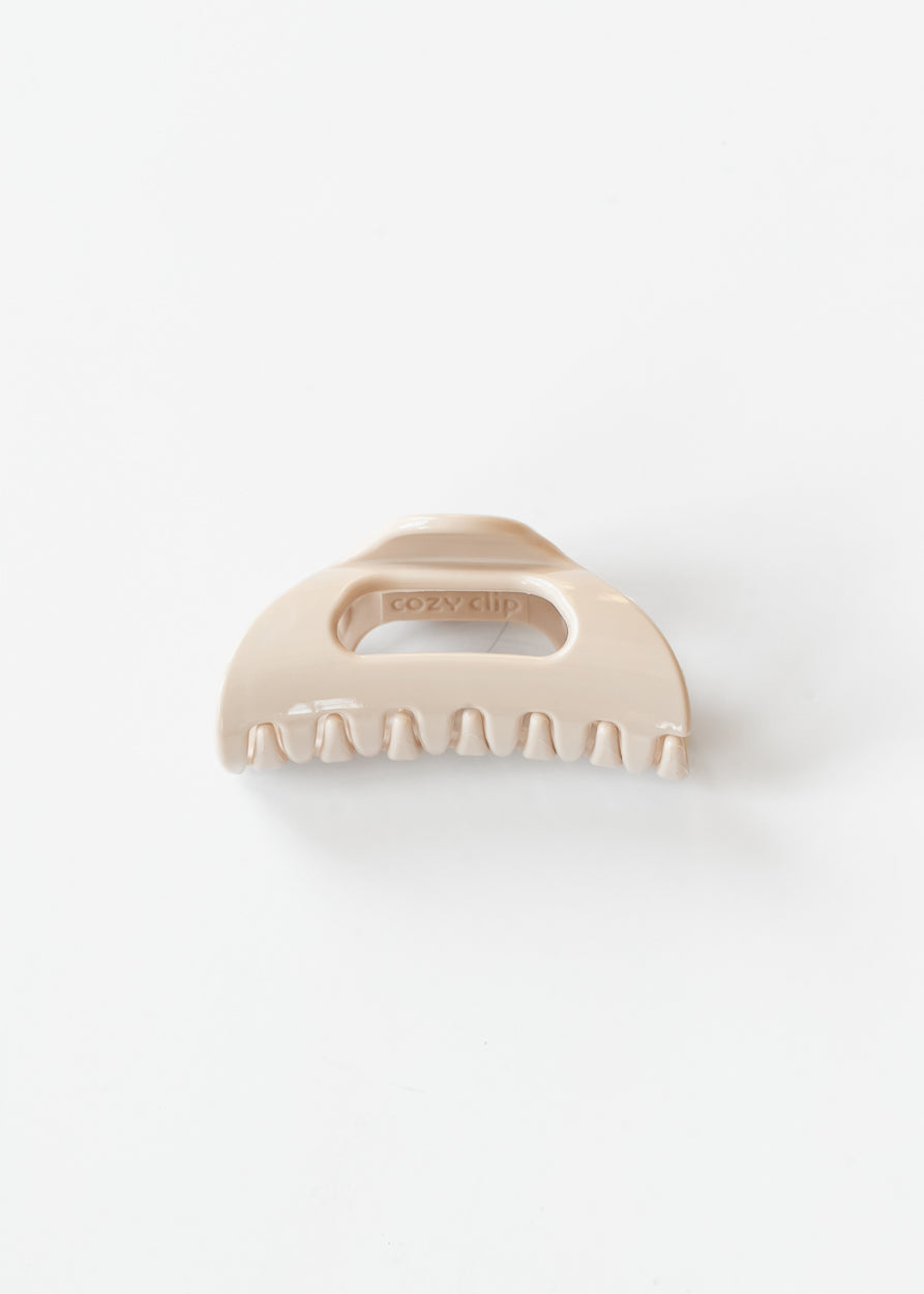 Blonde flexible claw clip shown from the front with curved claws and open center detail.
