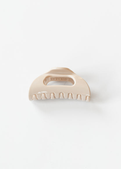 Blonde flexible claw clip shown from the front with curved claws and open center detail.
