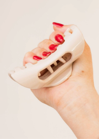 Blonde claw clip bent in hand to show its soft, flexible construction.
