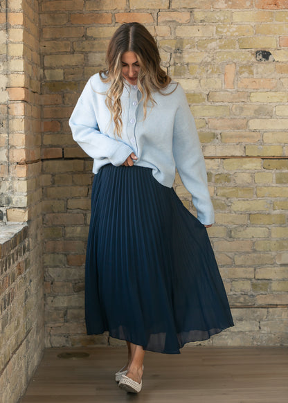 Navy flowy midi skirt with fine pleating and an elastic waist, styled with a button-front cardigan.