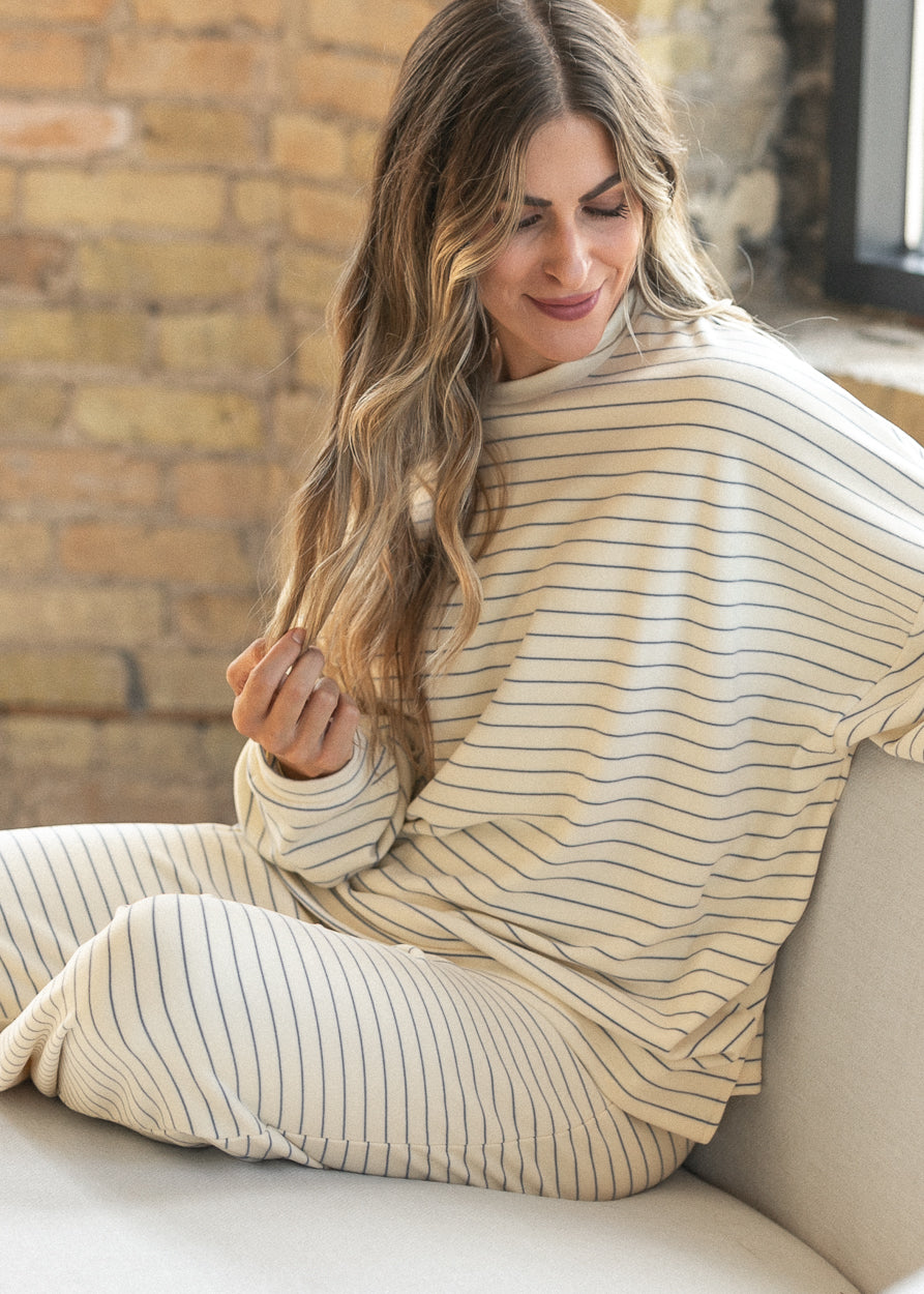 Side view of ivory striped long sleeve top showing the roomy oversized silhouette.