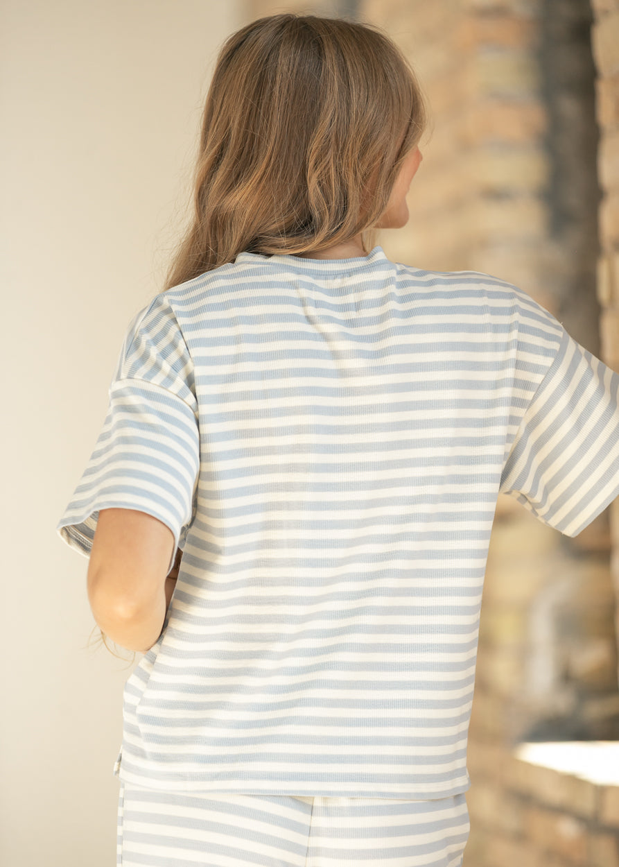 Back of light blue striped tee showing relaxed fit, dropped shoulders, and hip-length hem.