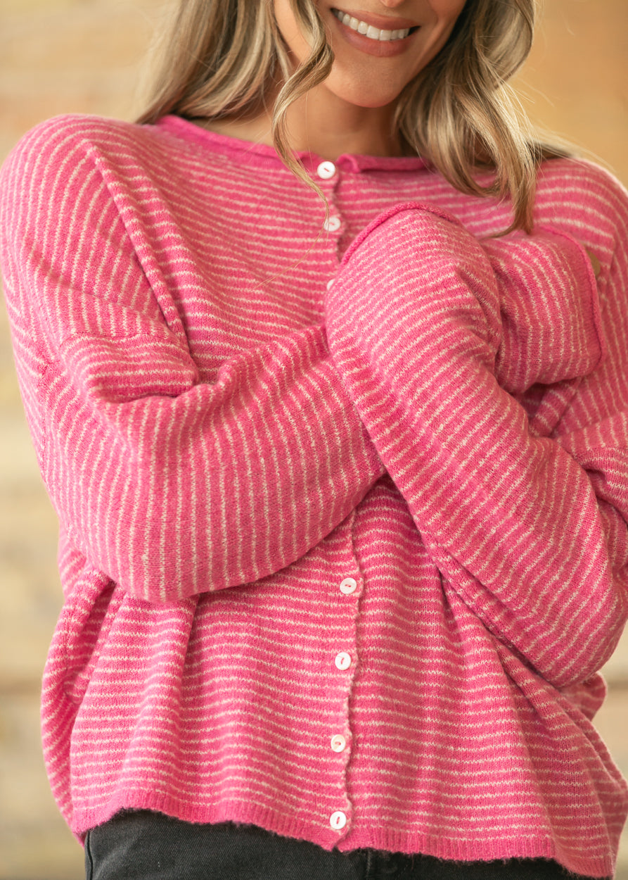 Close-up of bubblegum pink striped cardigan showing soft knit texture, buttons, and relaxed sleeves.
