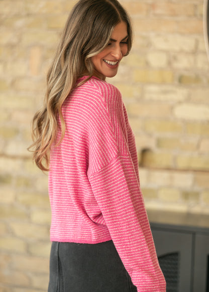 Bubblegum pink striped cardigan shown from the side with dropped shoulder seams and relaxed long sleeves.