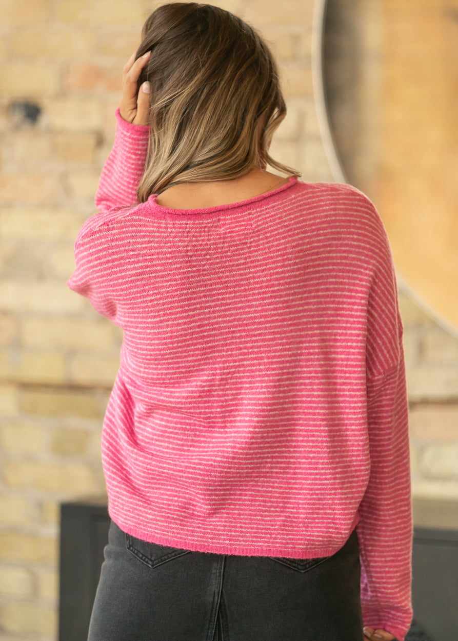 Back of bubblegum pink striped cardigan showing relaxed fit, dropped shoulders, and hip-length hem.