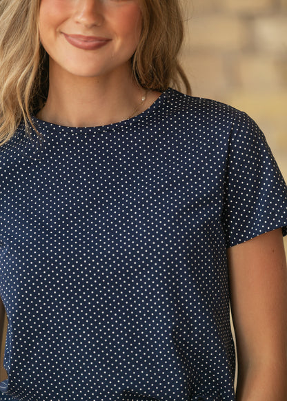 Close-up of navy polka dot jersey tee showing the crew neckline, short sleeves, and tiny white dot print.