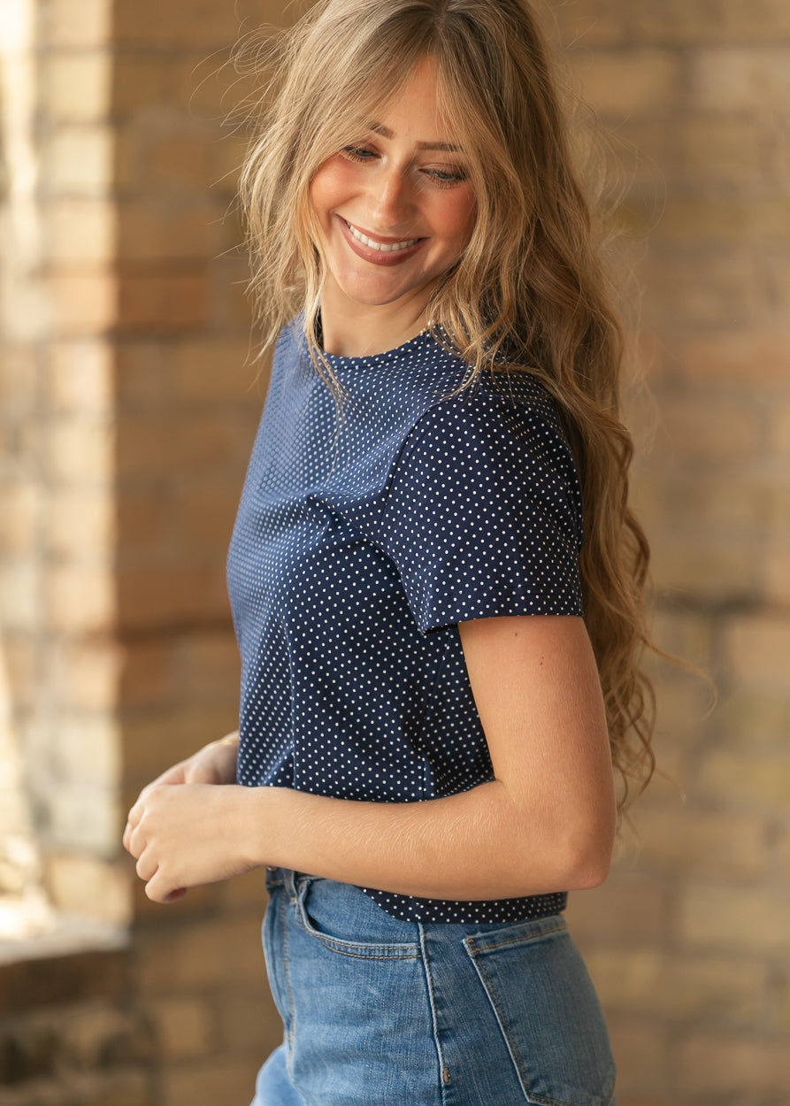 Navy polka dot jersey short sleeve tee shown from the side, styled with a medium wash denim skirt.