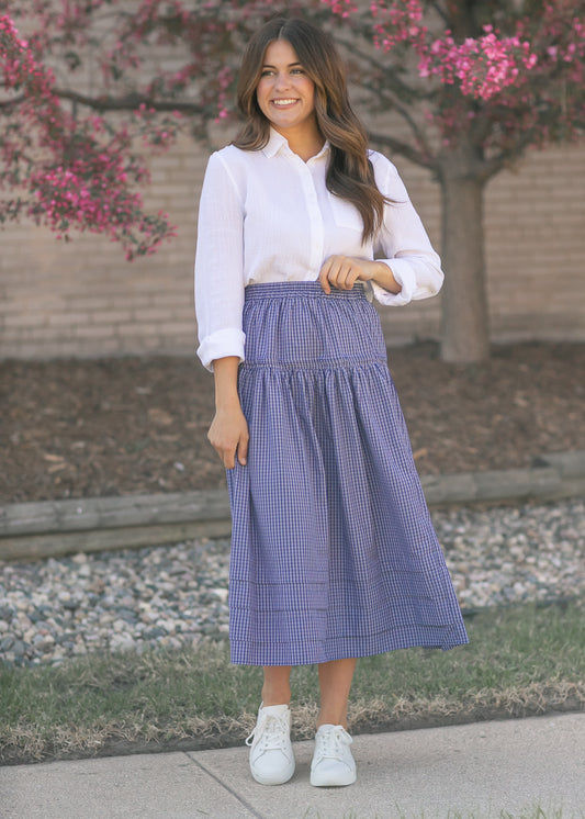Blue and white checker midi skirt with smocked waistband styled with a white button down top and white sneakers.