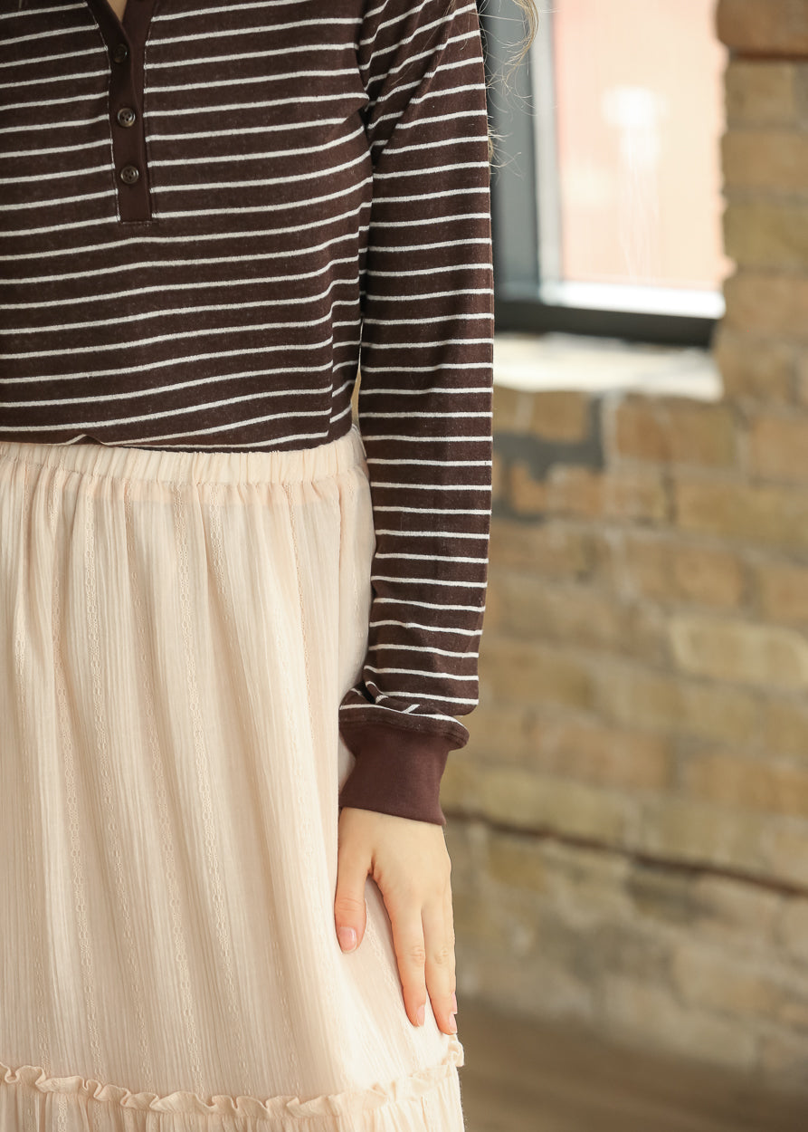 Close-up of Aeris striped top showing brown button-placket neckline and cream stripes.