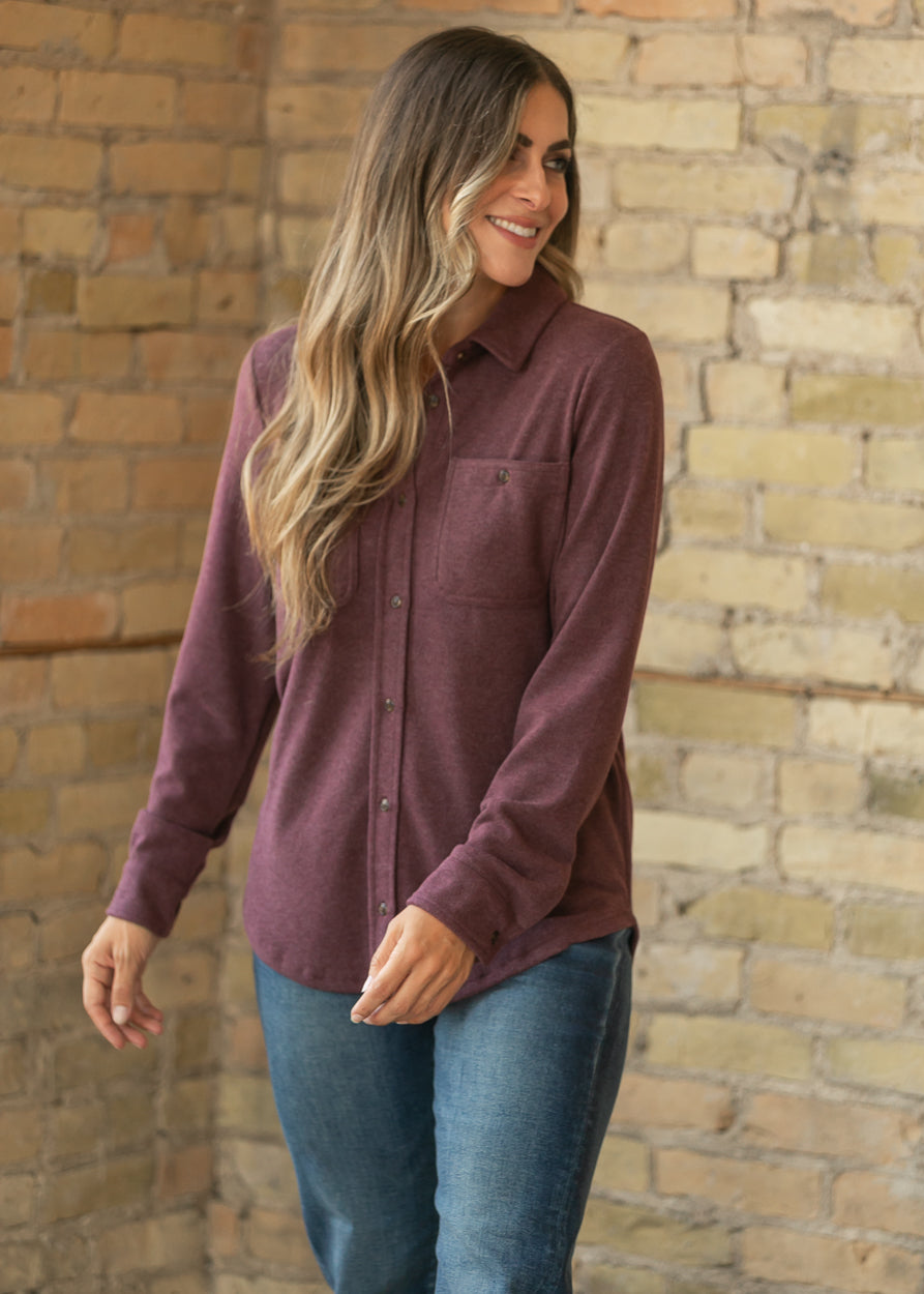 Burgundy long sleeve button up top with loose silhouette and hip-length curved hem.