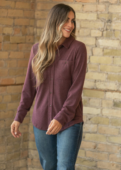 Burgundy long sleeve button up top with loose silhouette and hip-length curved hem.