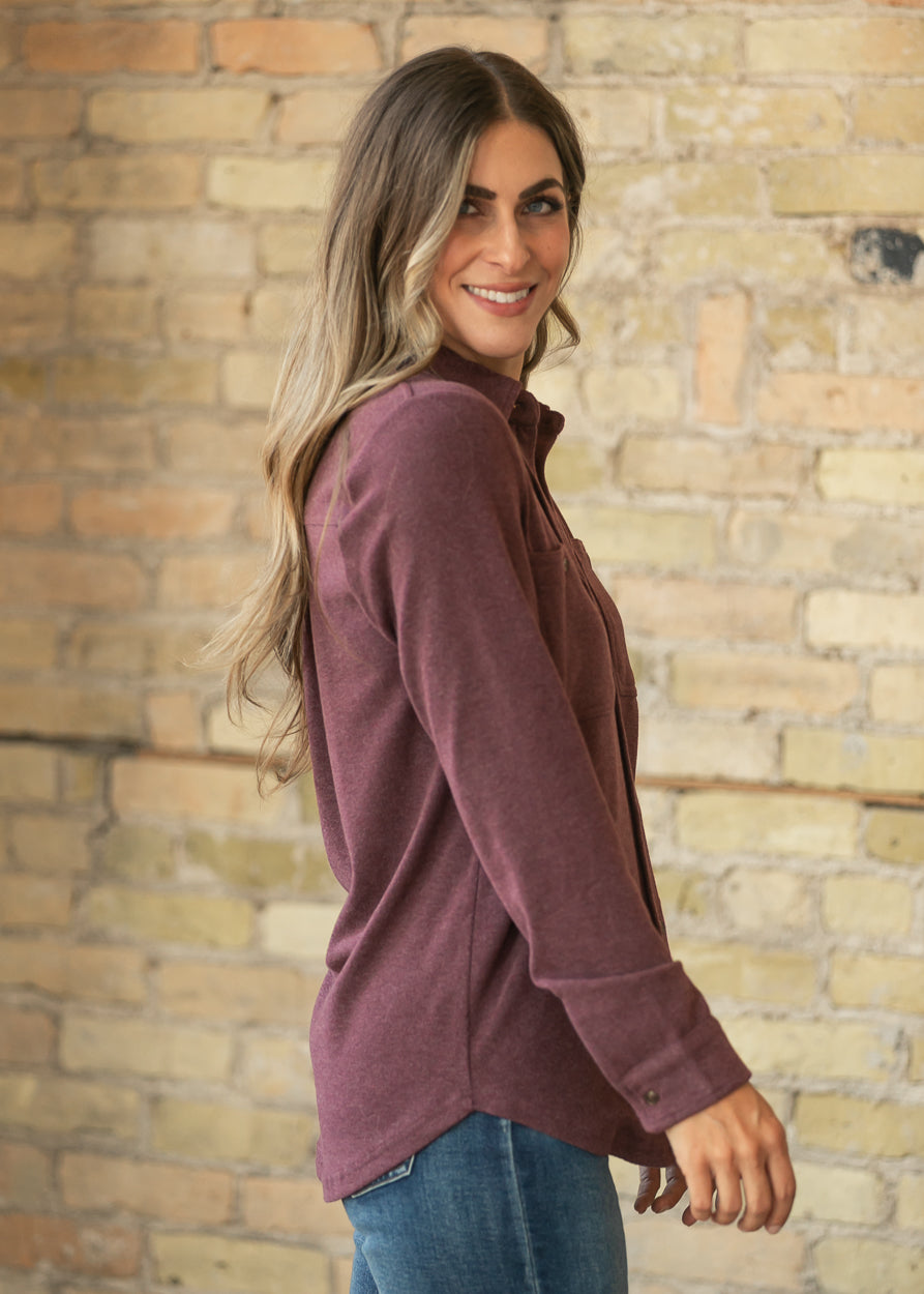 Side profile of burgundy button up top showing the long sleeves, button cuffs, and relaxed drape.