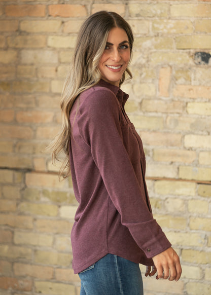 Side profile of burgundy button up top showing the long sleeves, button cuffs, and relaxed drape.