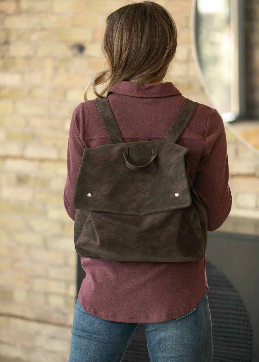 Vintage chocolate brown matte backpack worn on the back with adjustable shoulder straps and top carry handle.