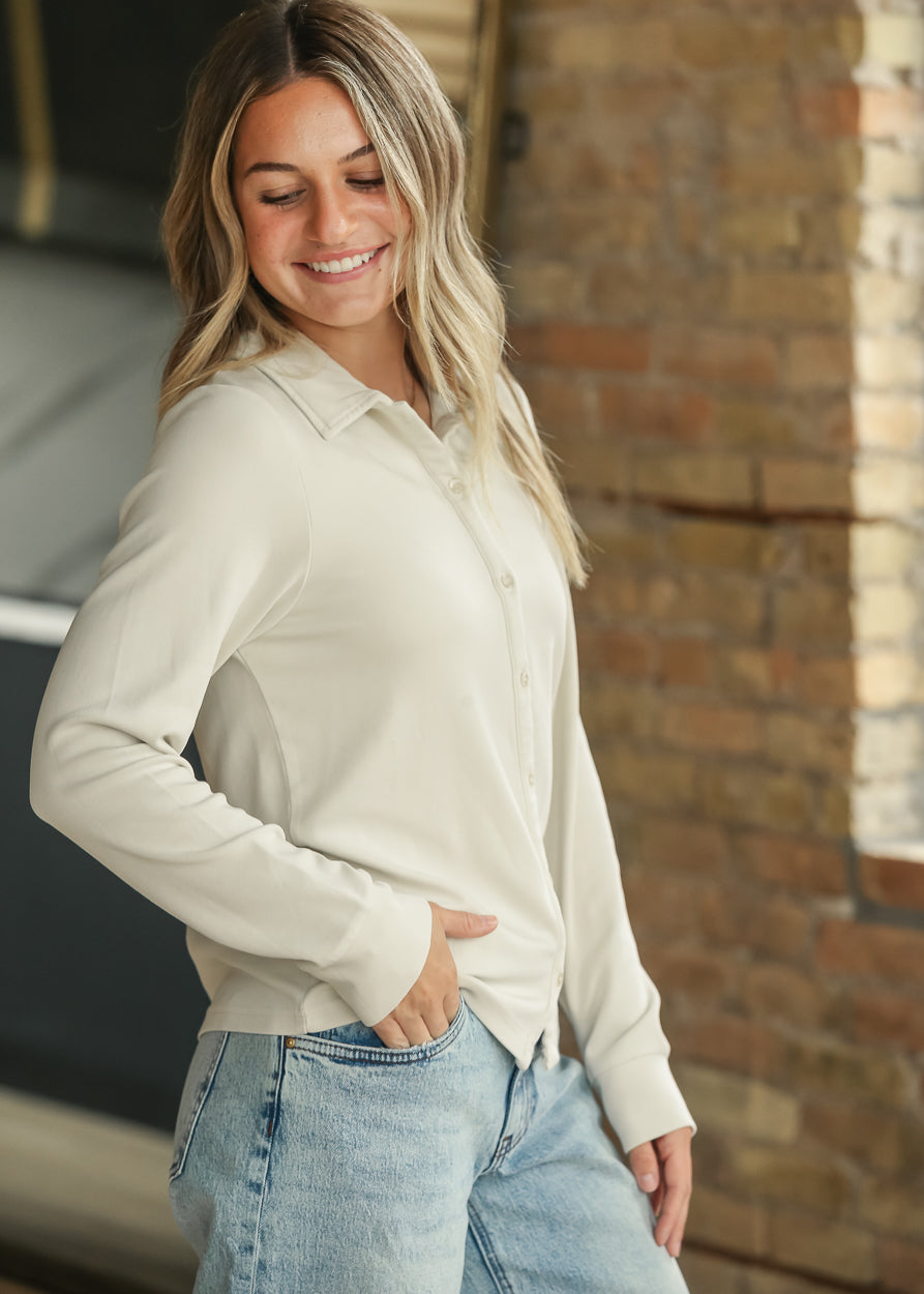 Cream long sleeve button-up shirt styled casually with light wash denim.