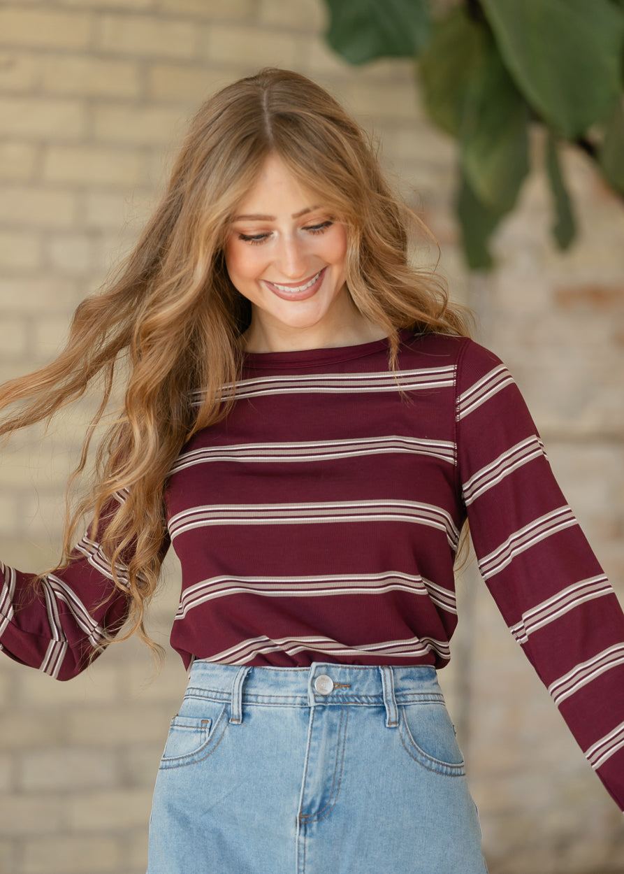 Maroon multi stripe long sleeve top with crew neckline and fitted silhouette, styled with a denim maxi skirt.