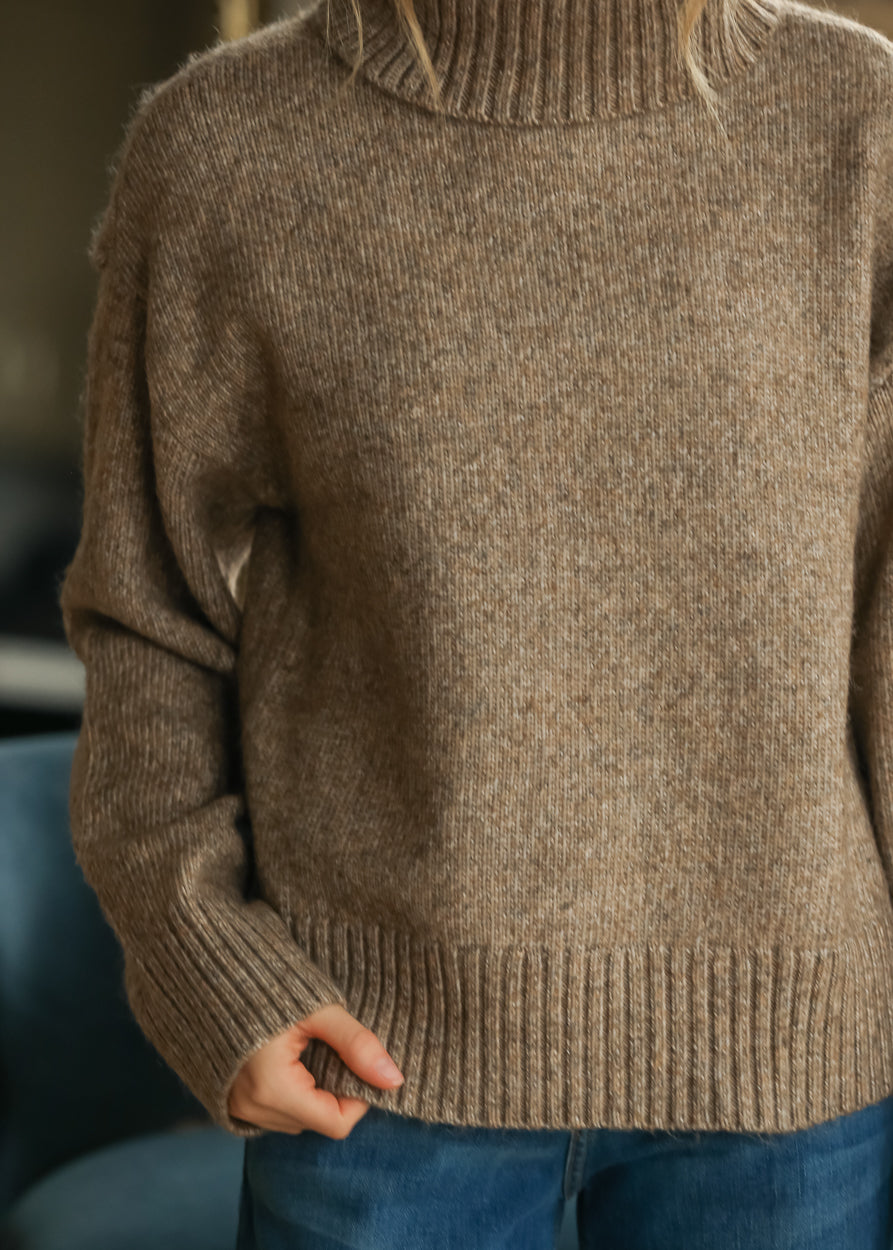 Sandstone knit turtleneck sweater with relaxed fit, ribbed hem, and foldover neckline.