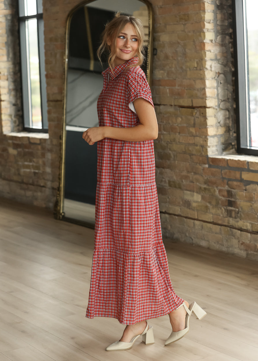 Red gingham tiered midi dress with button front, collared neckline, and ankle-length hem.