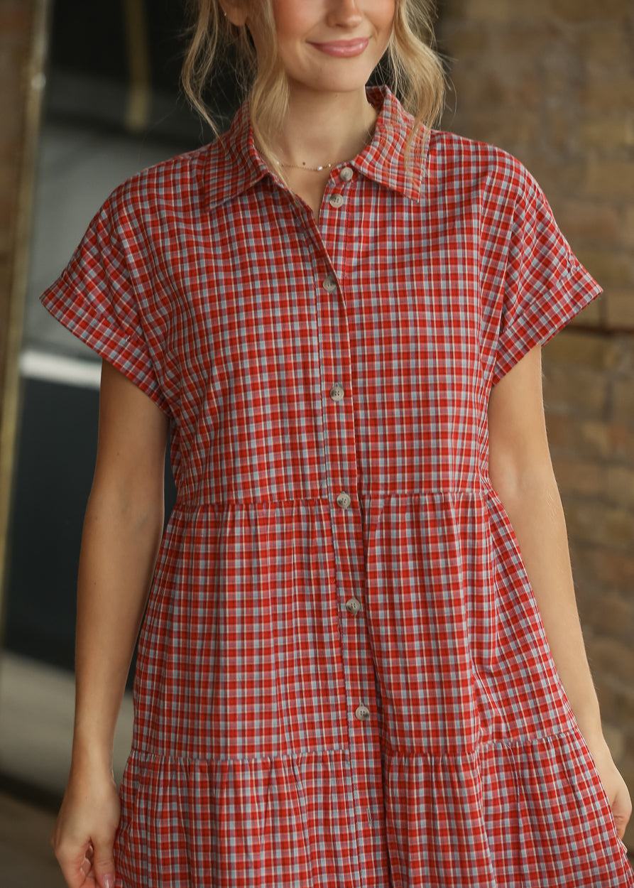 Red gingham shirt midi dress styled with cream heels, showing the tiered skirt and side silhouette.